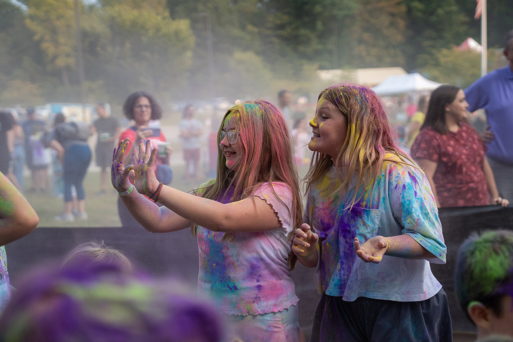 Two female students covered in paint showing off how much they have on them