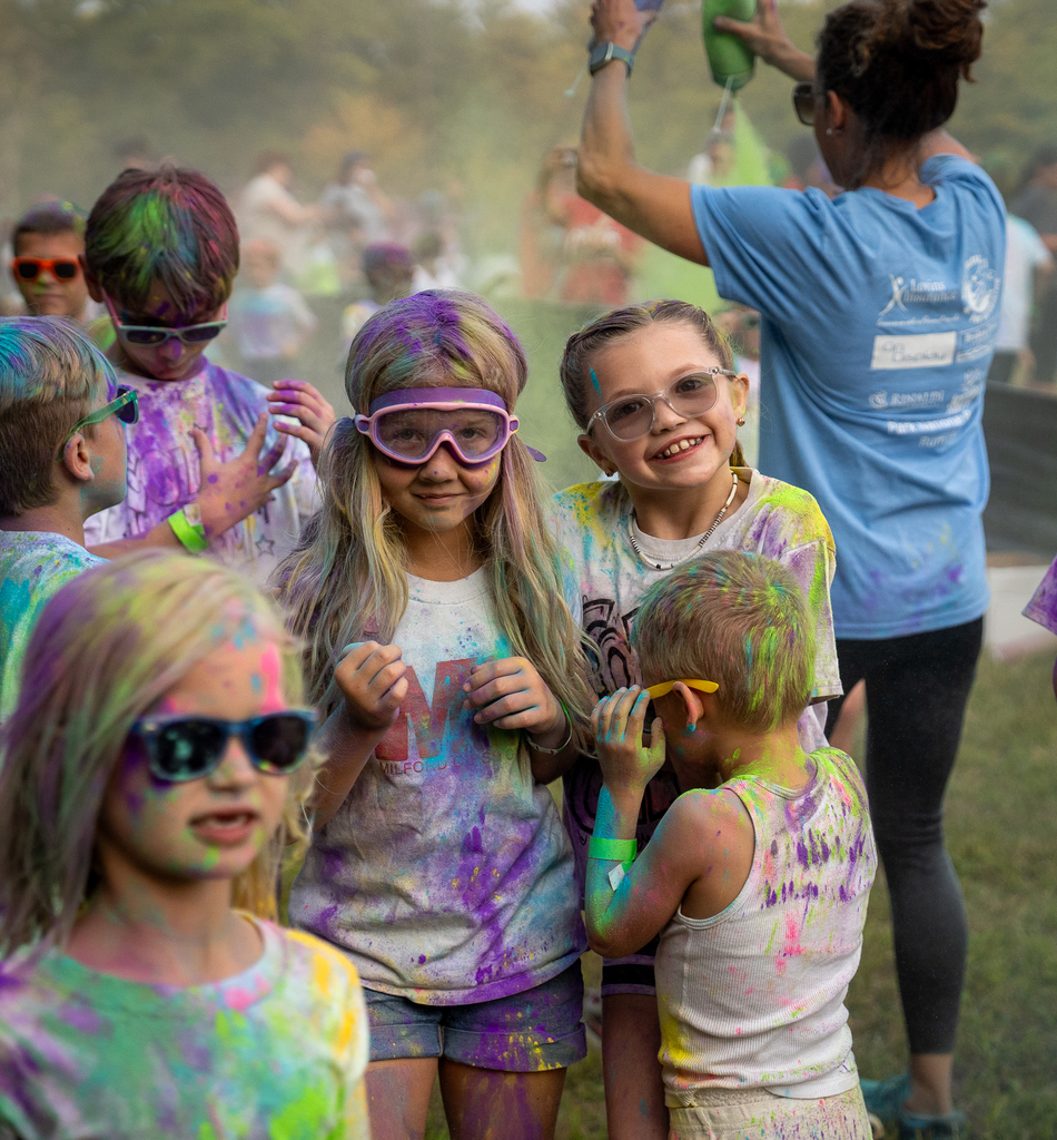 Two Girls smiling. One wearing goggles both covered in paint