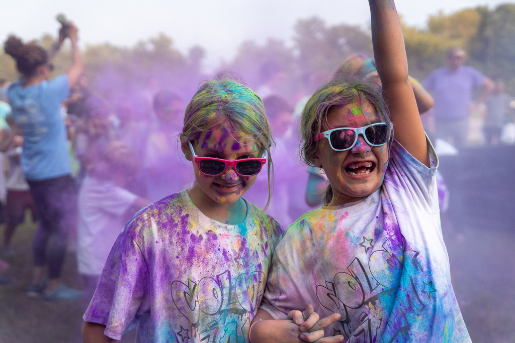 Two kids covered in paint one smiling with their arm up