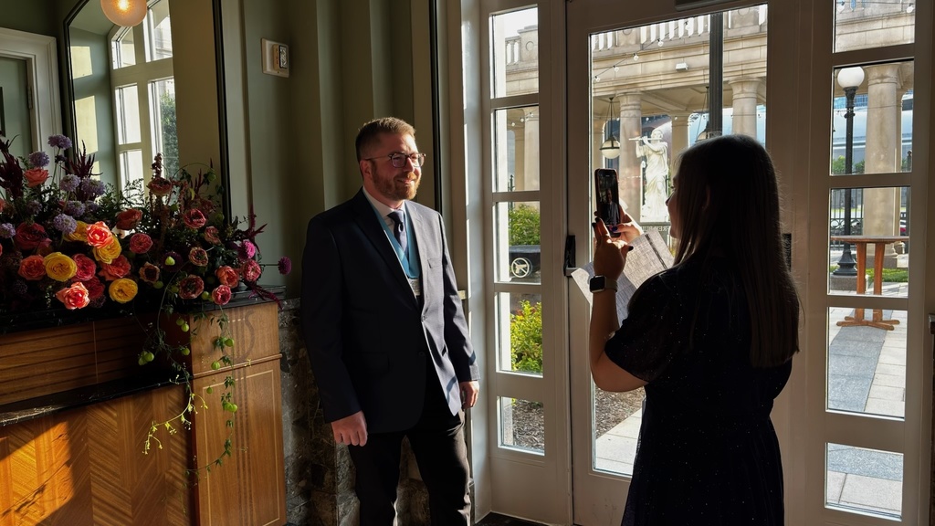 A man in a suit smiling while getting his photo taken