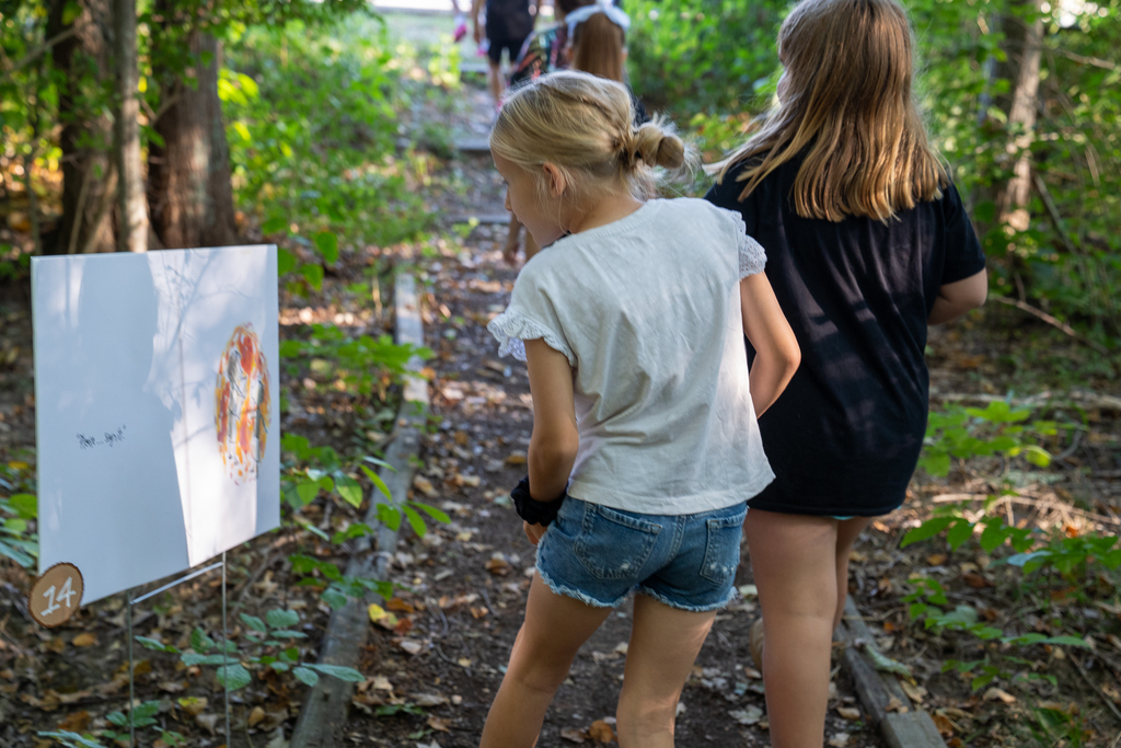 Girl looking at book sign in the middle of the woods