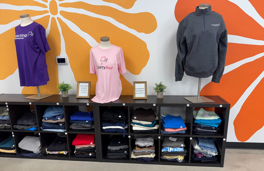 Some model clothes and t shirts saying "Carry Her" in front of a flowery wall