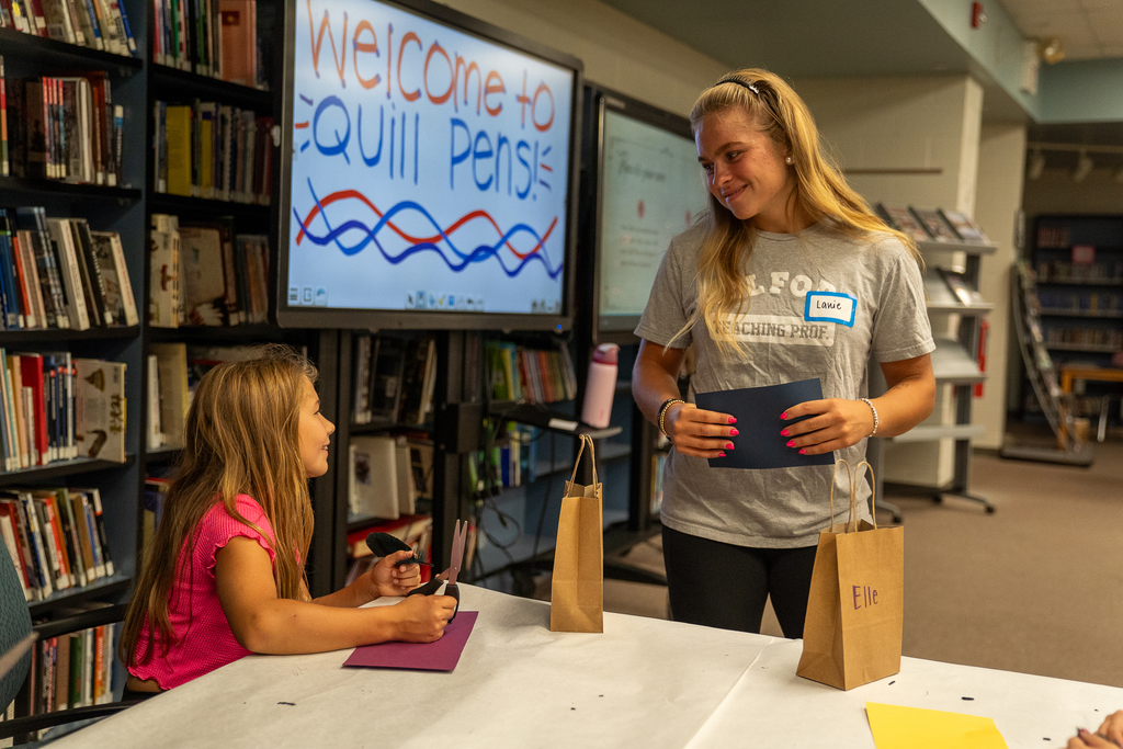 A blonde hair girl smiling at a child