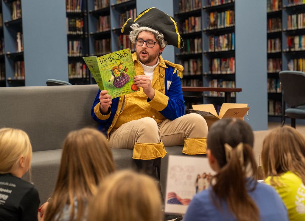 A man dressed like George Washington reading to a group of children