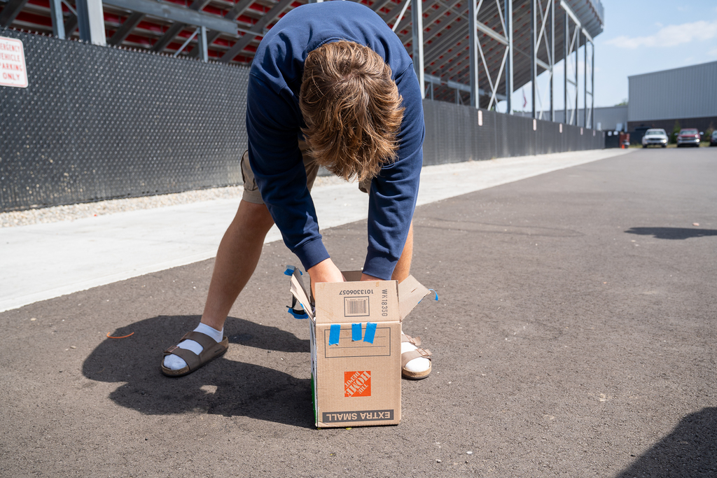 Student in blue sweatshirt picking up a box