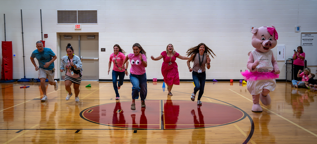 A group of female teachers all in pink running in the gym
