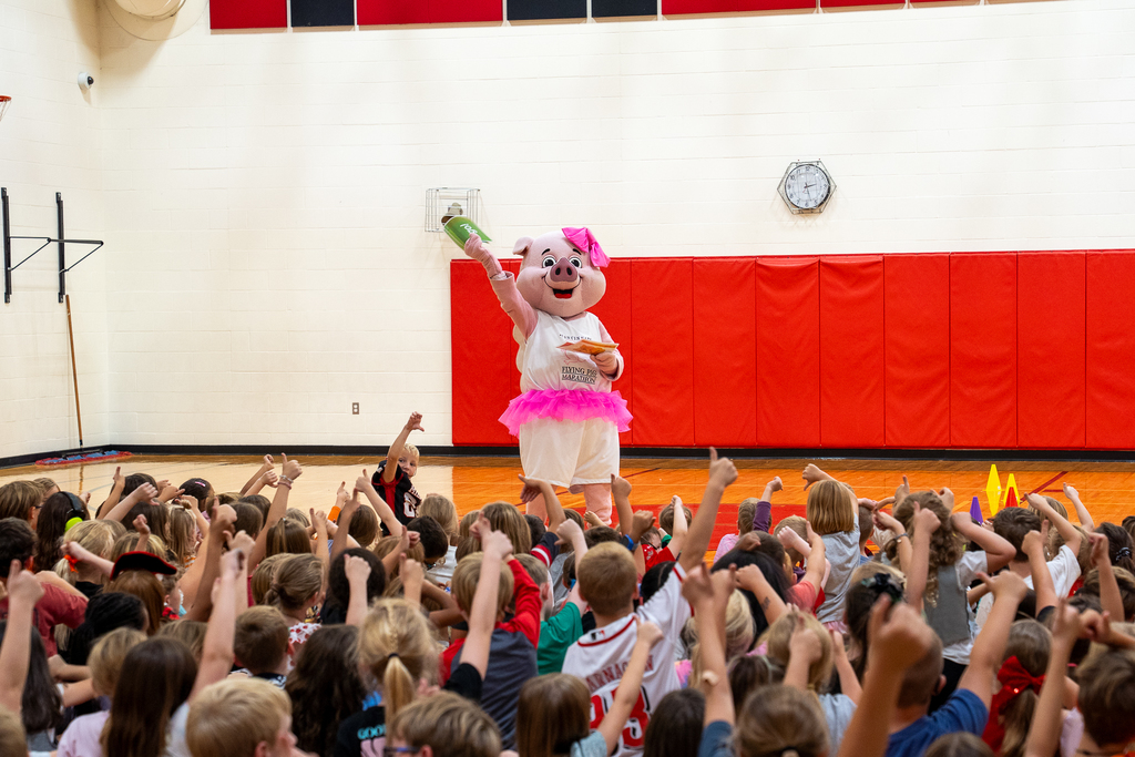 a pig mascot in a room of children