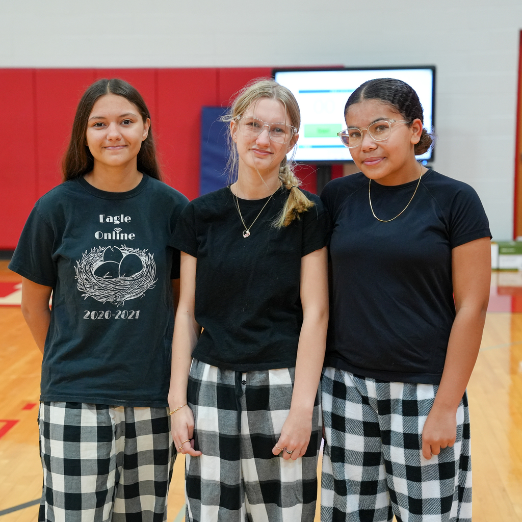 three girls standing with matching black and white checkered bottoms with black t-shirts