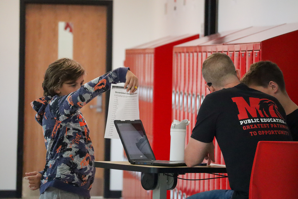 A boy showing his paper to a teacher
