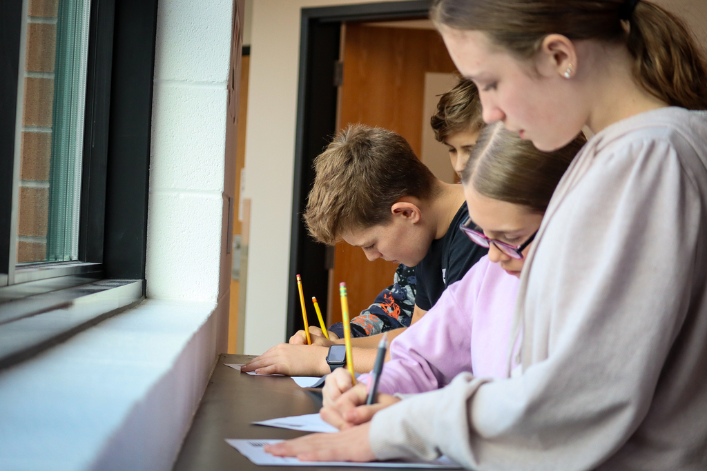 Kids at a table top writing on paper