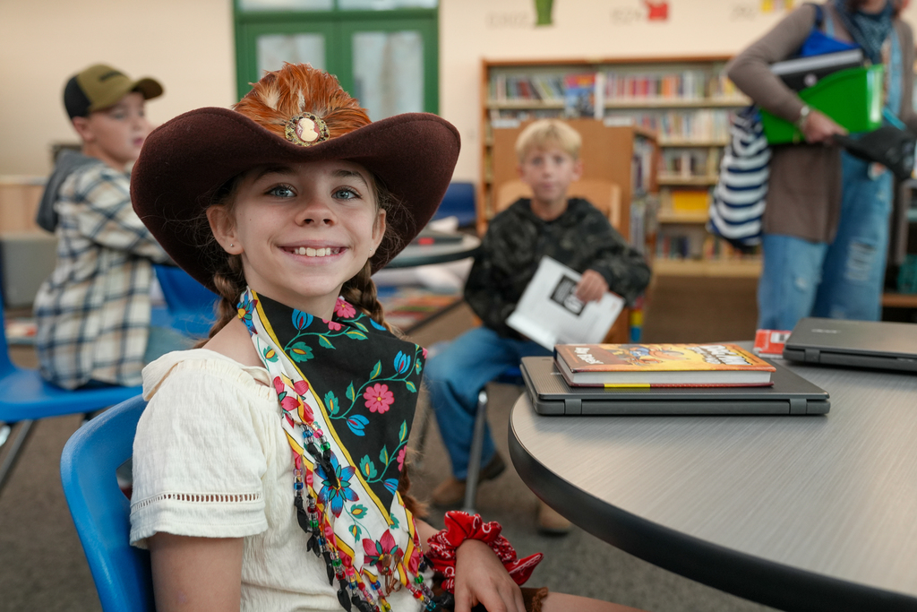 A girl wearing a cowboy hat and floral print handkerchief 