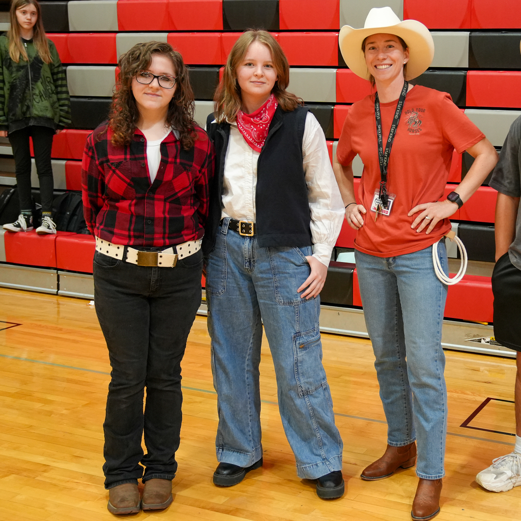 two teenage girls dressed up as cowboys next to a woman wearing a cowboy hat and small rope