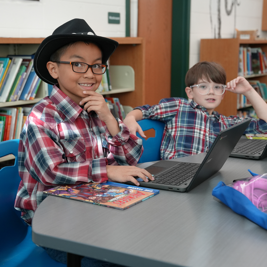 A small child with glasses wearing a flannel and a cowboy hat