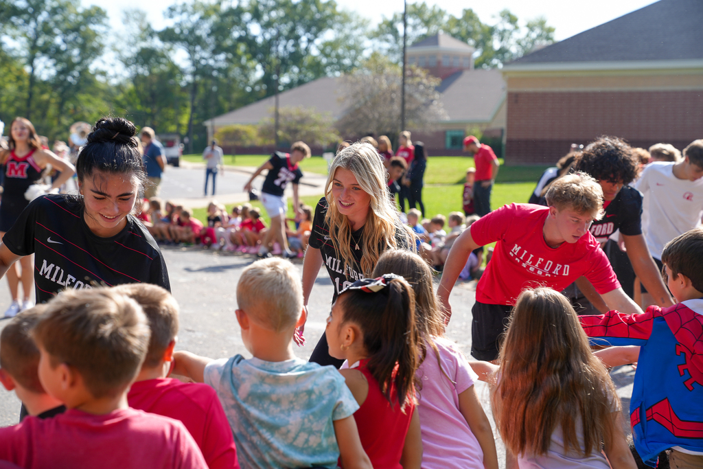 a girl with blonde hair giving high-fives to students