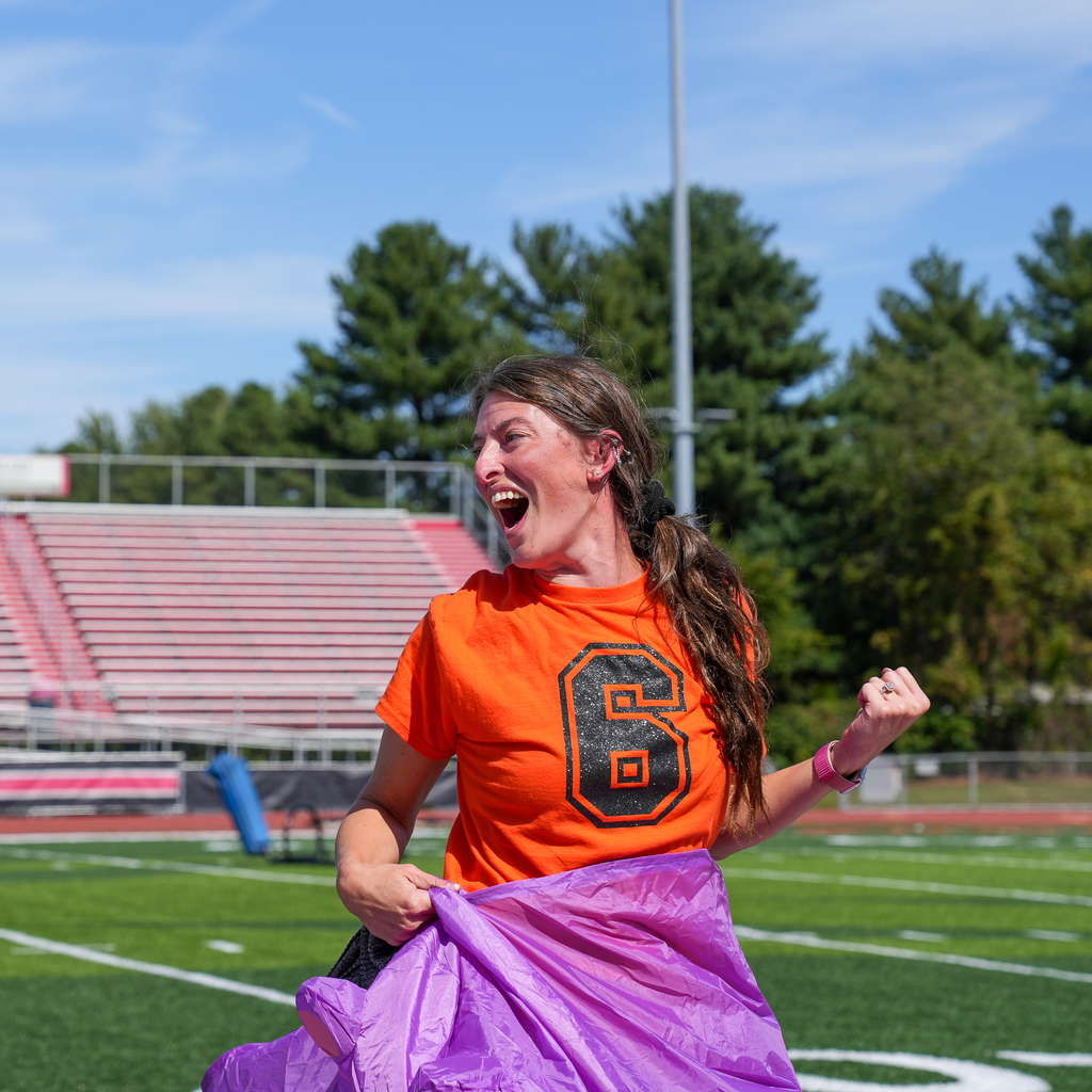 woman in orange cheering as she comes out of a purple costume