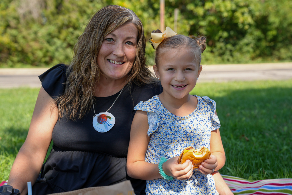A woman with a child holding a burger 