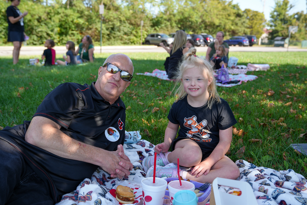 A grandpa and his kid outdoors eating 