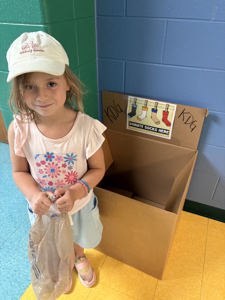 a small kindergartener holding a bag in front of a box 