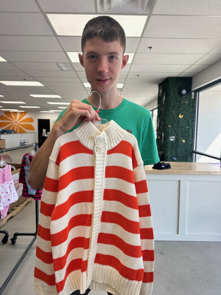 a boy holding a red and white stripped sweater 
