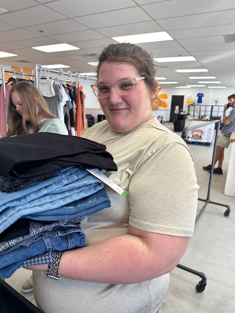 girl with glasses holding folded clothes 