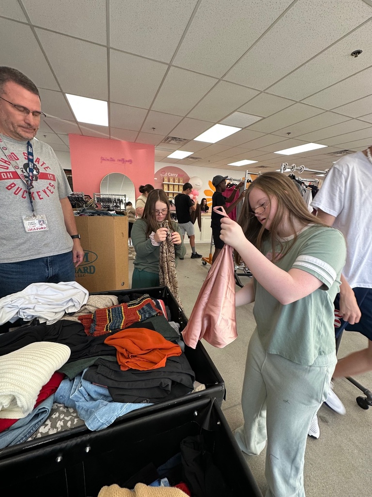 two girls with glasses sifting through clothes bins
