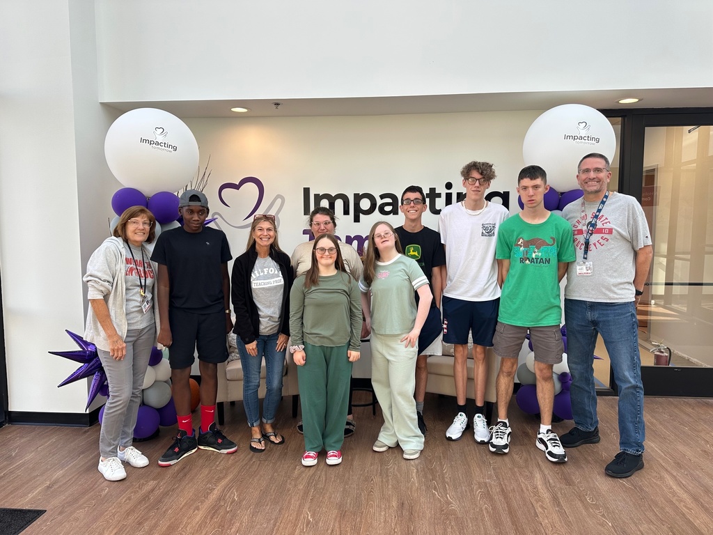 Group of people standing in front of Impacting tomorrow sign