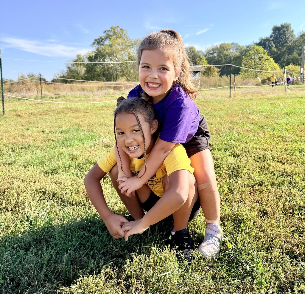 a small girl with a long ponytail on the shoulders of another small girl with braids
