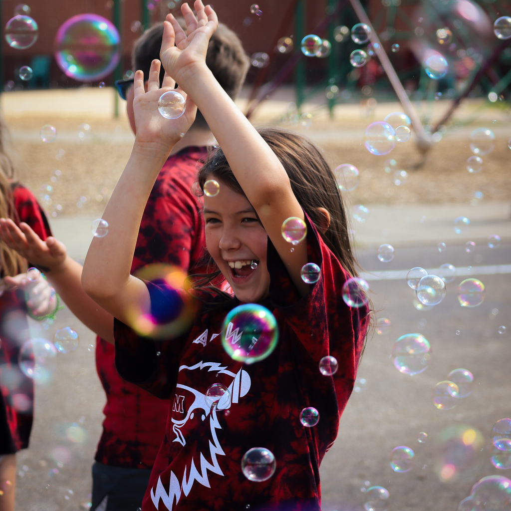 kid waiving her hands at bubbles