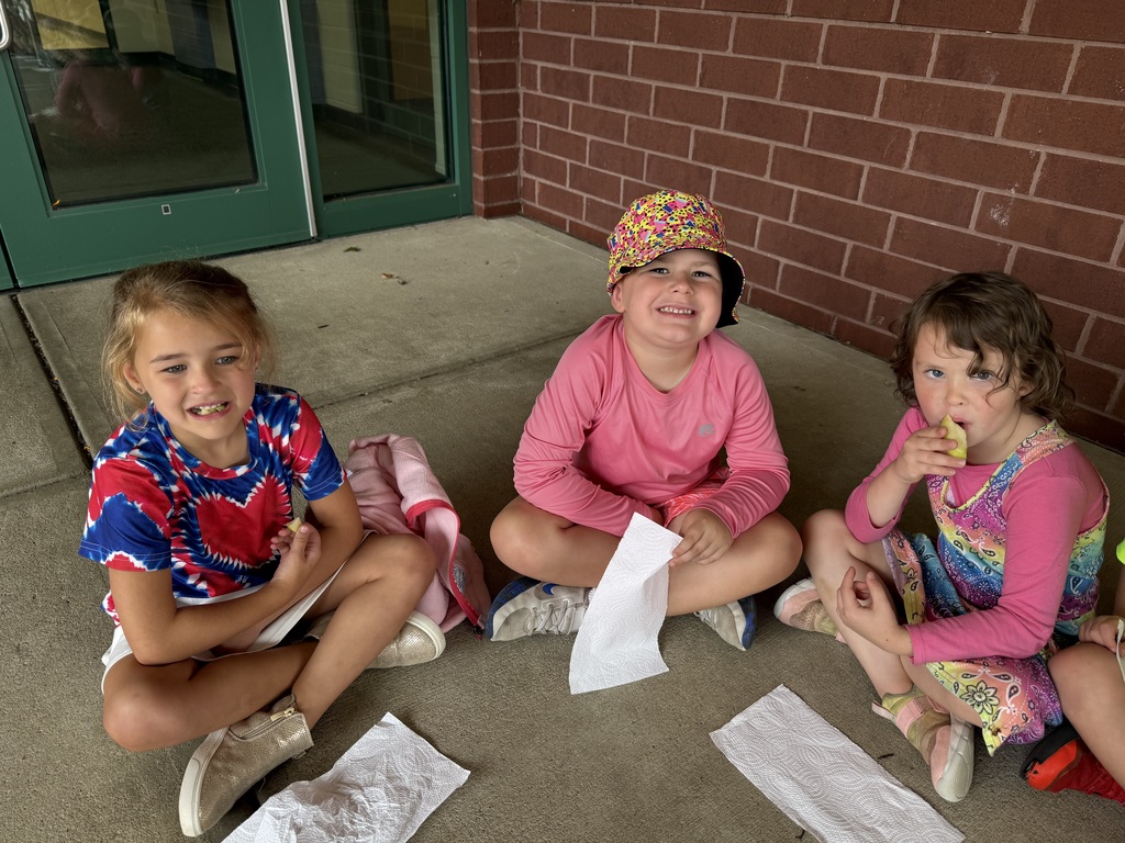 Three kids sitting on the ground