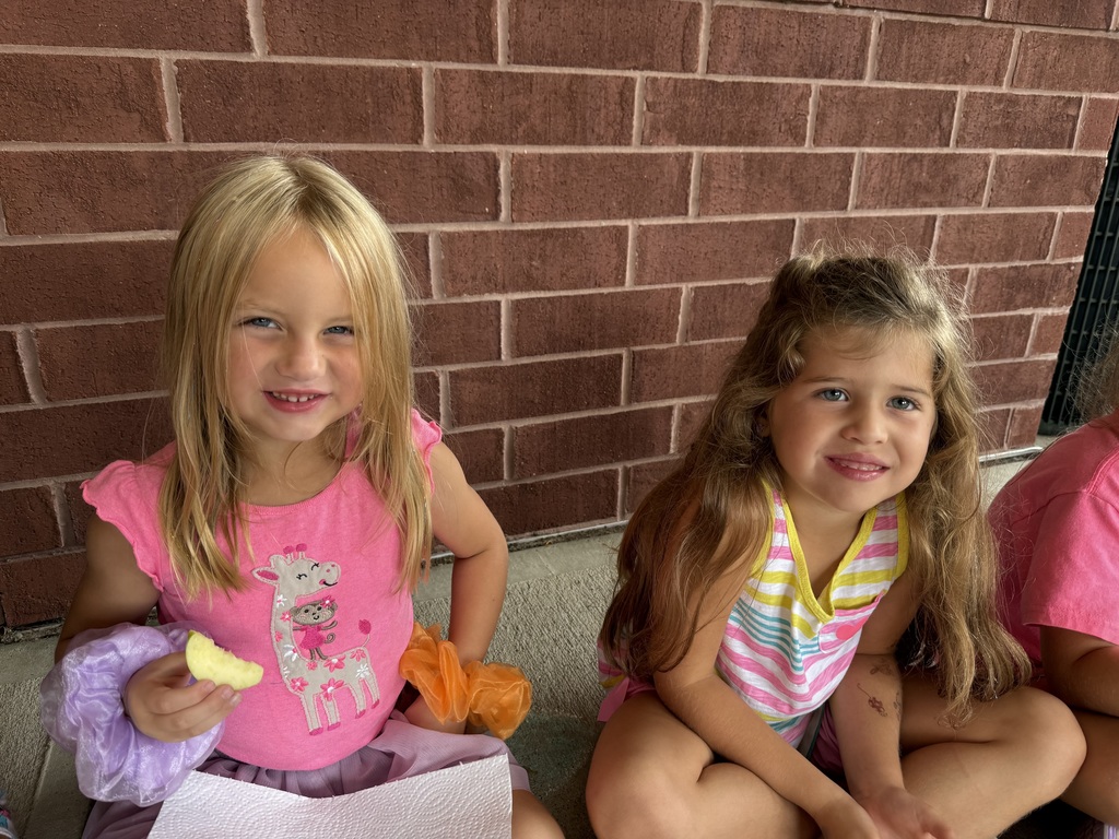Two girls sitting down smiling at the camera