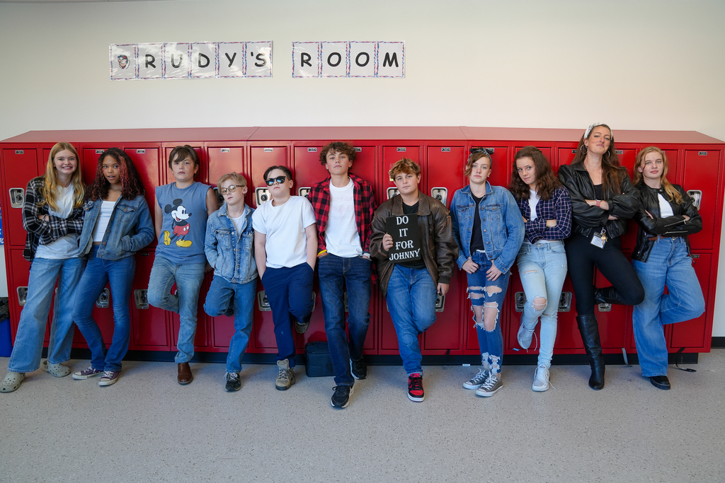 A group of kids all dressed in blue jeans looking like 50's "greasers"