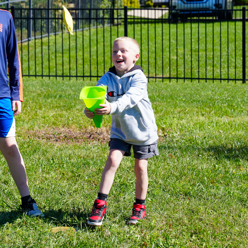 a boy trying to catch a hacky sack with a green cone