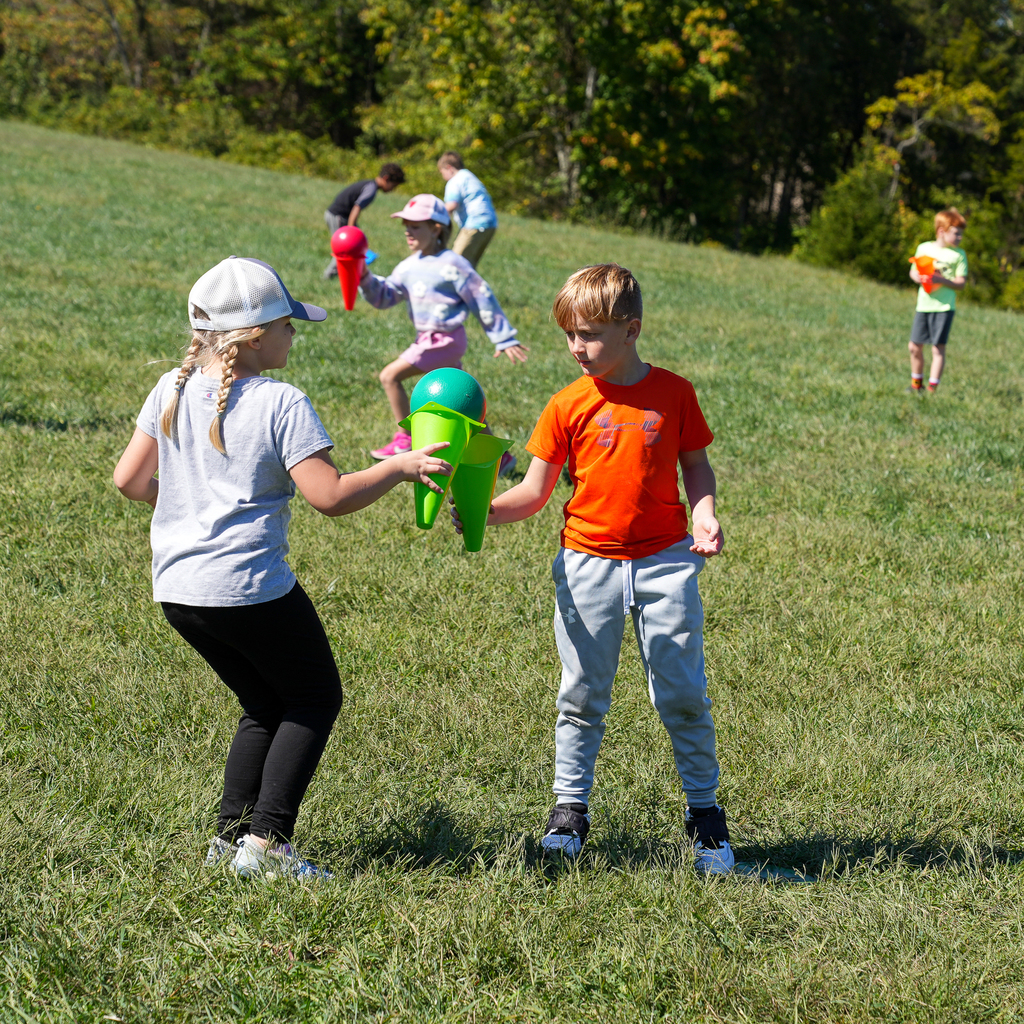 Two kids passing a small ball using the ends of cones