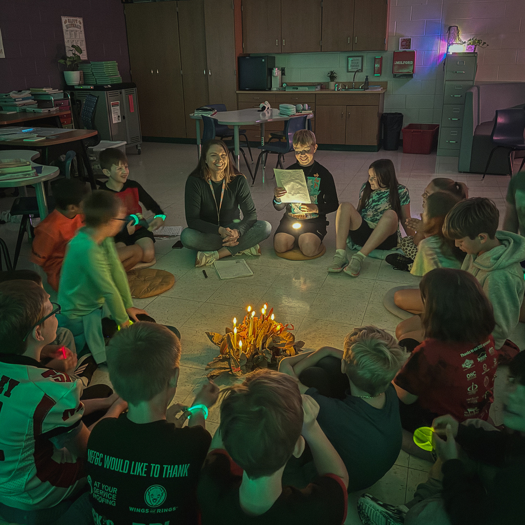 A big circle of kids with a bunch of fake candles in the center