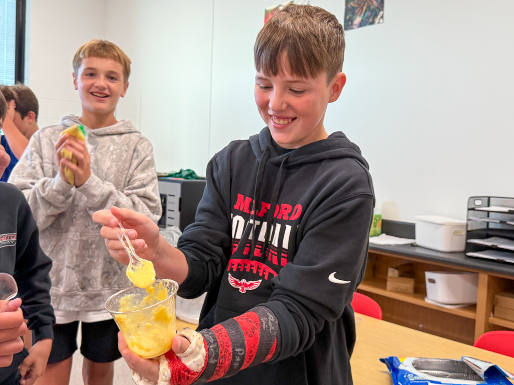 A kid in a cast smiling at yellow pudding