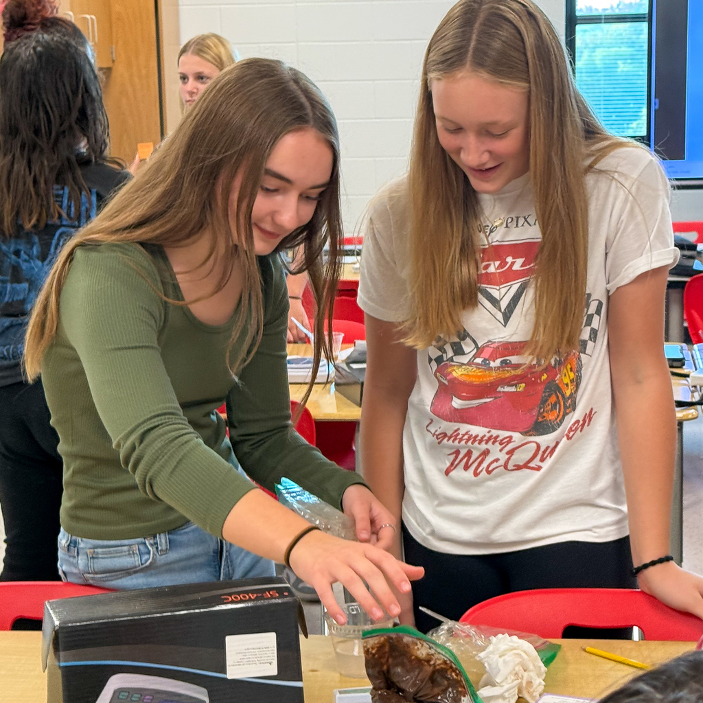 Two girls measuring brown pudding