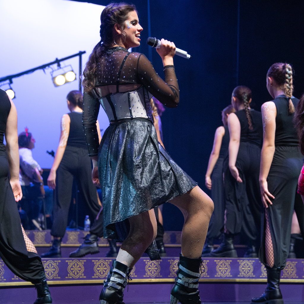 Brunette girl in a corset outfit singing on a stage