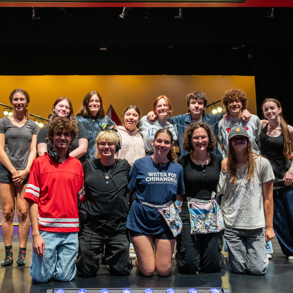 A group photo of teenagers on stage wearing clothes for a stagehand