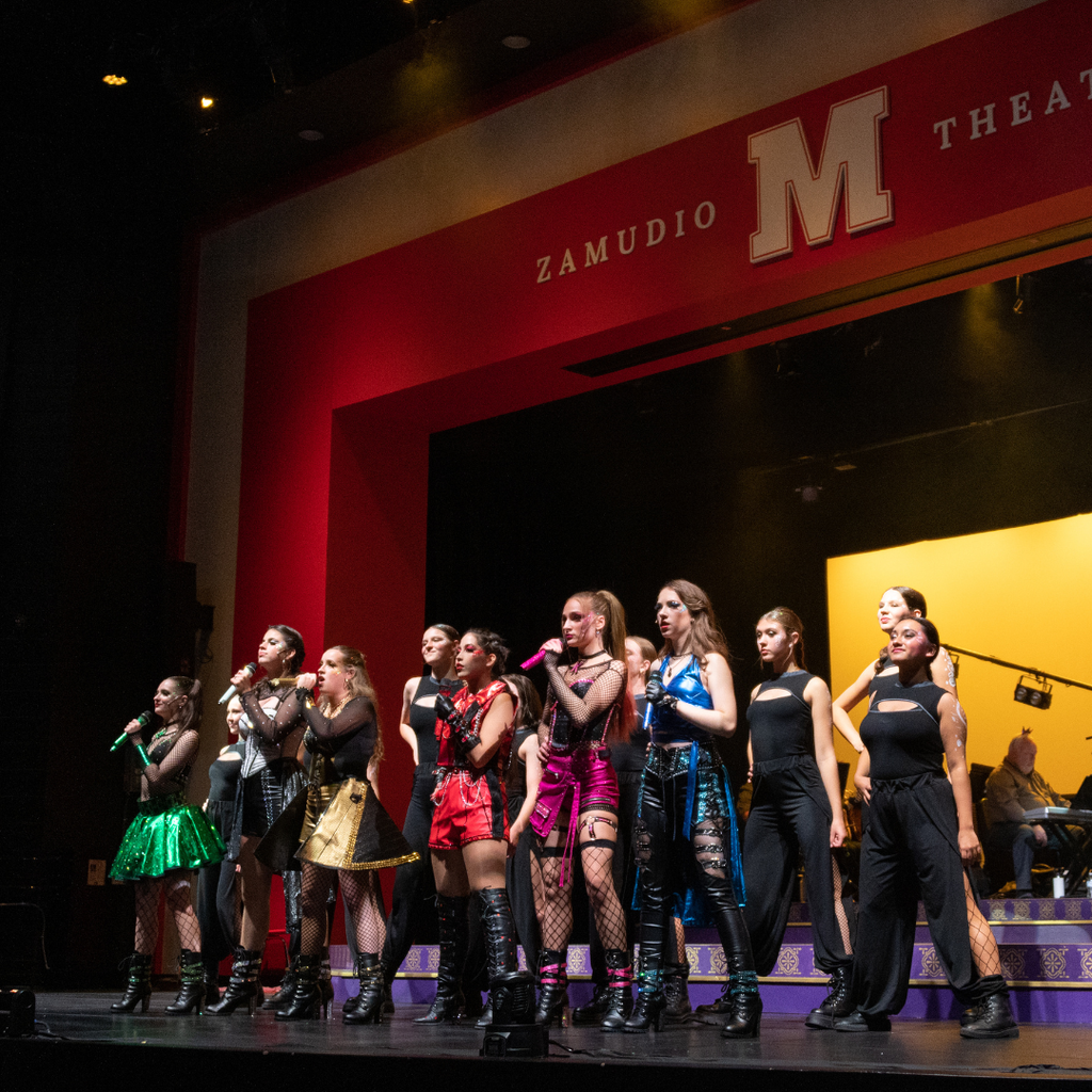 a cast of women in colorful outfits performing on stage