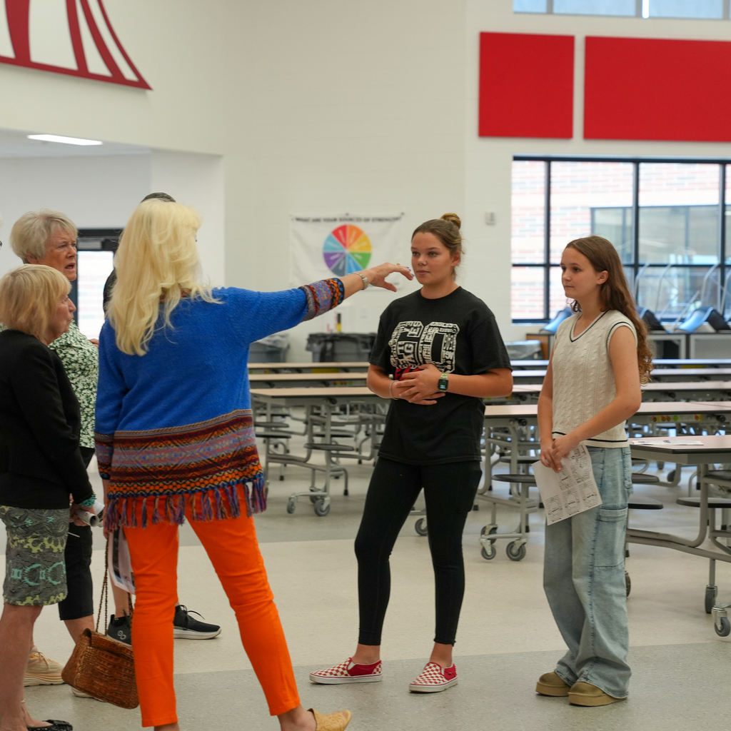 A woman pointing to something while two girls are talking