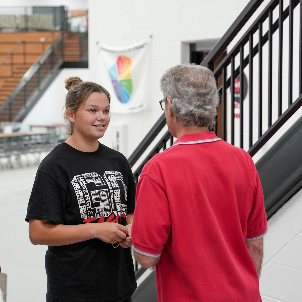 A girl in a black shirt talking to a senior man