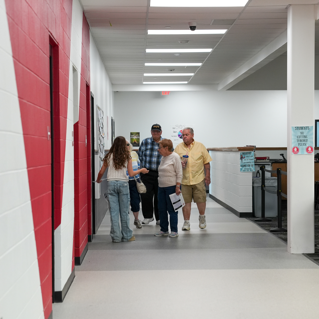 A group of seniors talking to a girl in a hallway