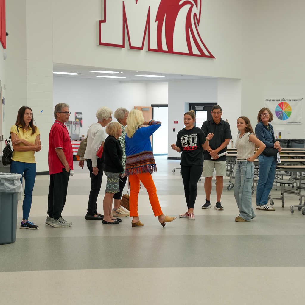 A group photo of seniors talking to a girl in a gym