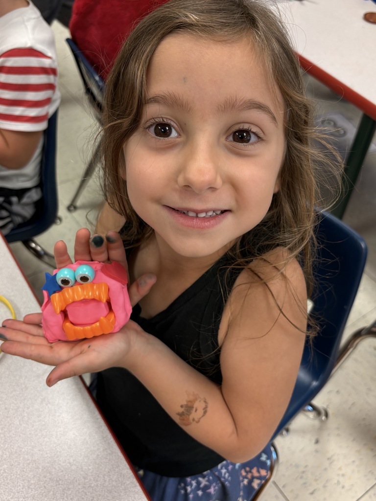 A girl presenting a pink play-doh monster