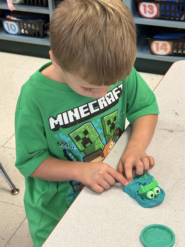 A boy working on a green play-doh monster