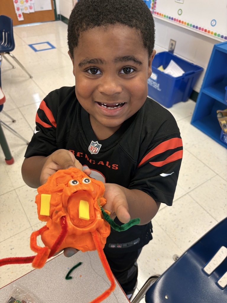 A boy wearing a bengals jersey holding out some kind of orange flower thing