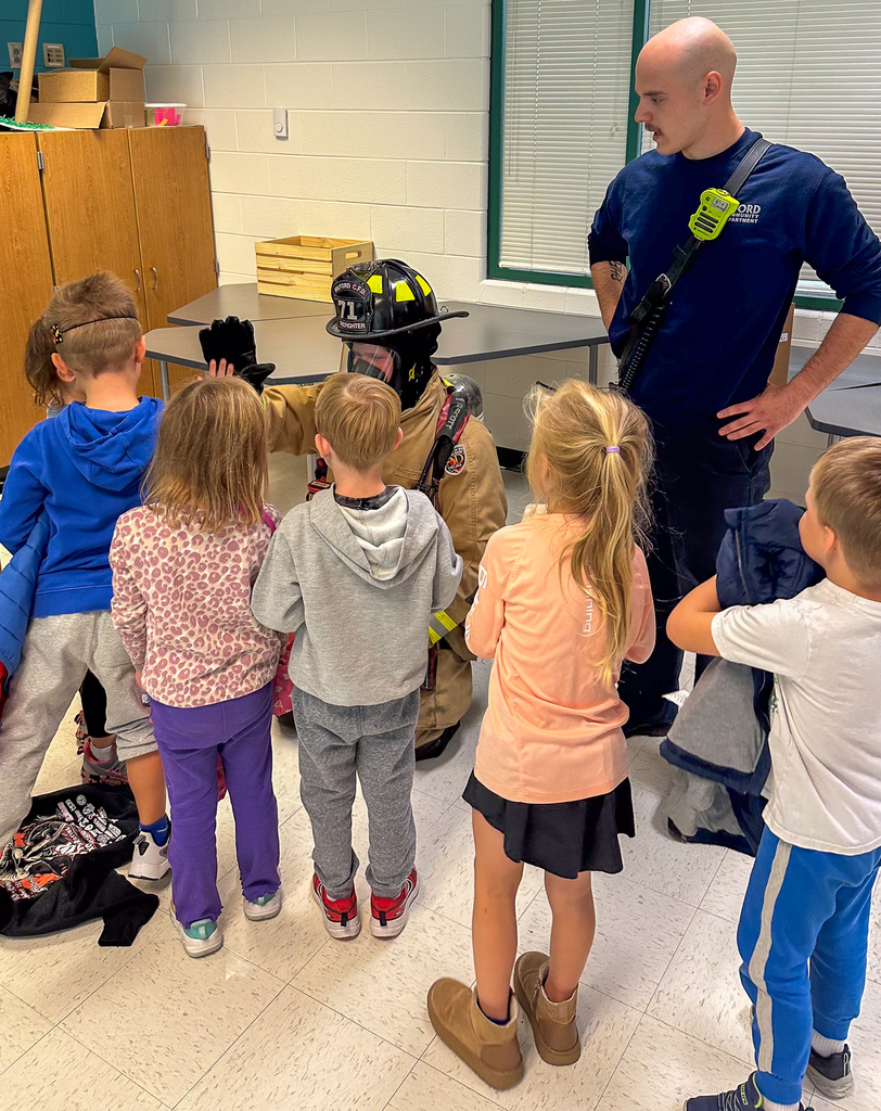 Kindergarteners high fiving a fire-fighter