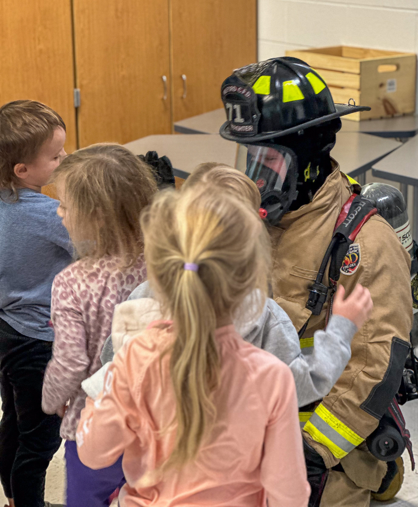 Kindergarteners high fiving a fire-fighter