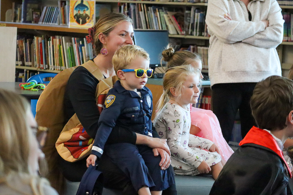 A woman dressed up like a donut holding a kid dressed up like a cop