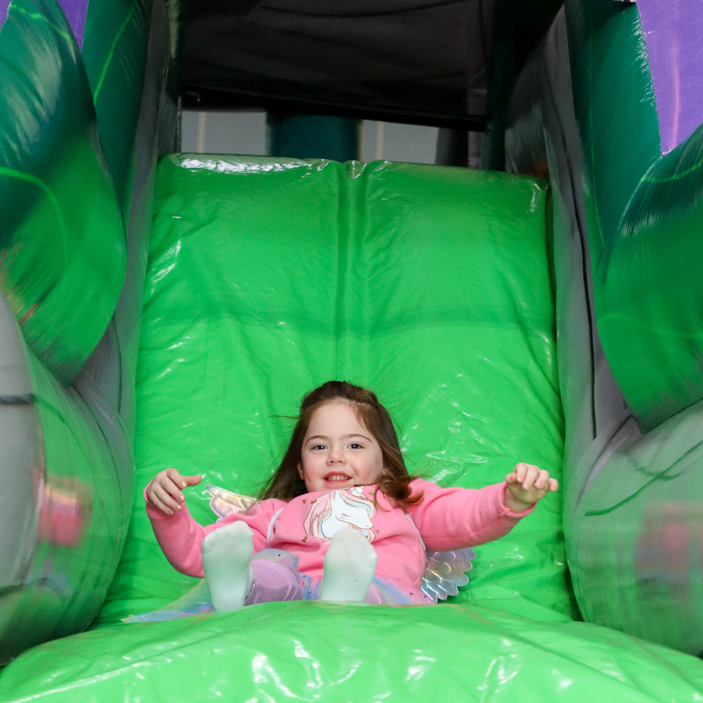 A student in pink sliding down an inflatable slide